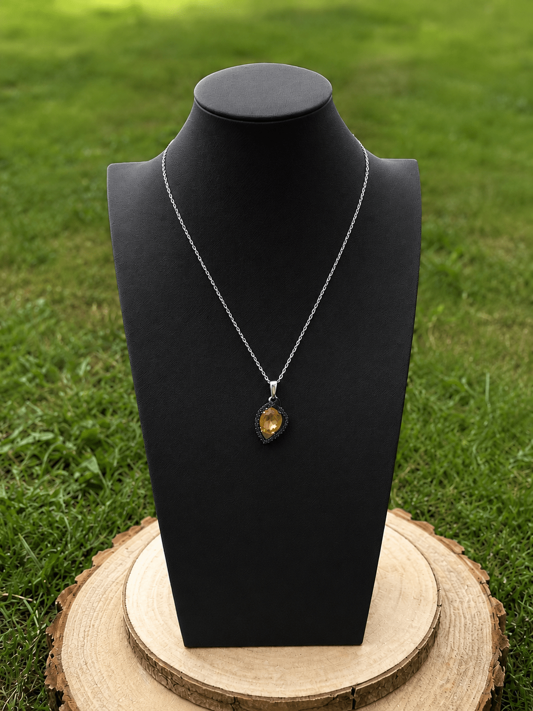 Pendentif en citrine naturelle facettée monté sur chaîne argentée, présenté sur buste noir. Bijou de lithothérapie apprécié pour favoriser l’abondance, la confiance, la motivation et le rayonnement personnel.