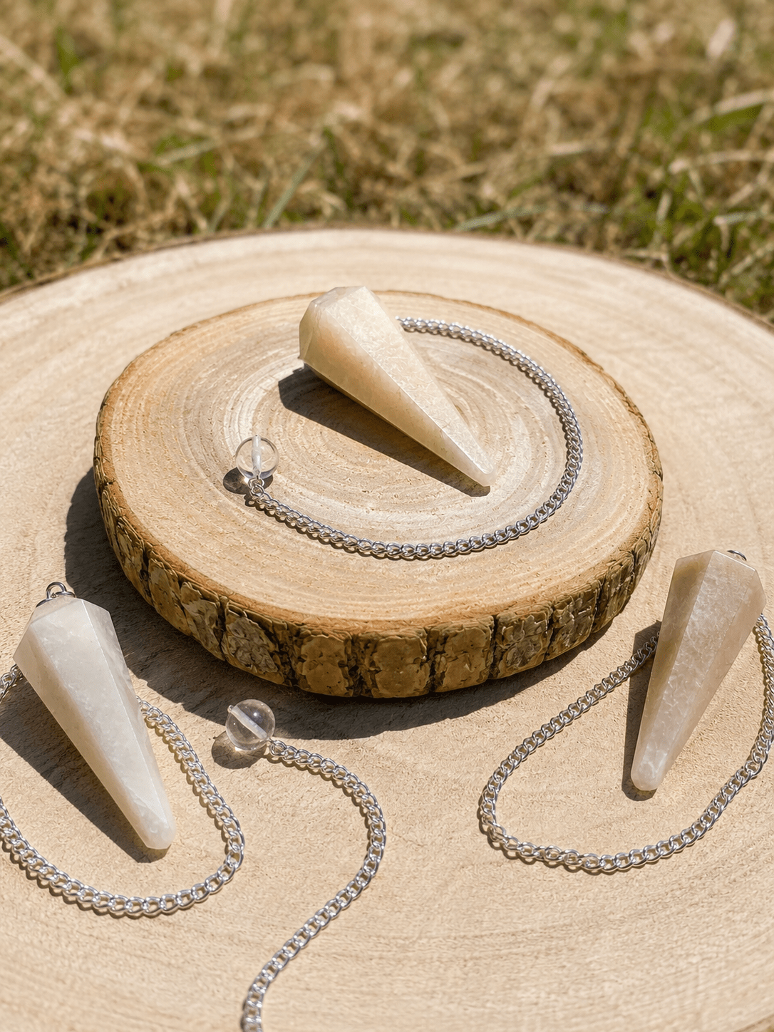 Collier avec pendentifs en pierre blanche sur rondin de bois, pose en extérieur; texte intègre les erreurs des débutants avec les runes et les pendules.